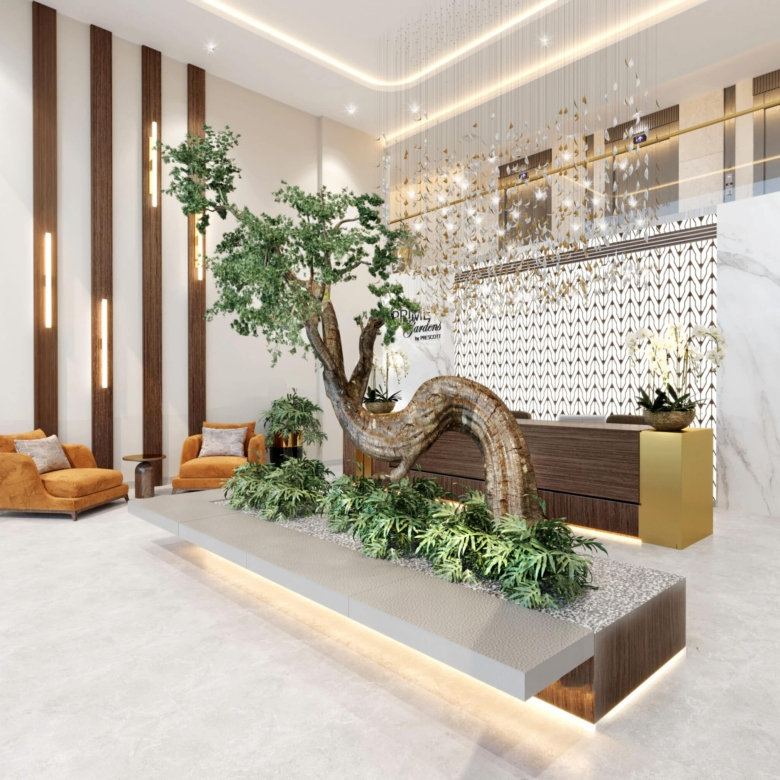 לובי מודרני ב-Prime Gardens, עם עץ פיסולי במרכזו, צמחייה ירוקה, דוגמאות גיאומטריות על דלפק הקבלה, נגיעות זהב ושיש, חיפוי עץ וכורסאות טרקלין בצבע צהוב חרדל. המקום מואר ומאוורר, עם עיצוב אלגנטי ועכשווי.