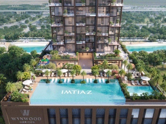 מבט אווירי על מגדל המגורים המודרני "Wynwood Horizon", הכולל בריכות גג, מיטות שיזוף, עצי דקל ומגרש משחקים — הכול מוקף בצמחייה עבותה ומשקיף על כביש מהיר המשתרע מרחוק. על הבניין ניתן להבחין בלוגו של IMTIAZ.