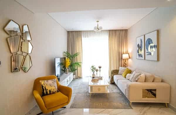 סלון מודרני ב-Gardenia Livings עם כורסה צהובה, ספה בצבע בז’, תמונה מופשטת על הקיר, מראה גיאומטרית, טלוויזיה, עציצים, שולחן קפה עמוס בחפצי נוי ווילונות מהרצפה עד התקרה המכניסים אור טבעי. סלון מודרני ב-Gardenia Livings עם כורסה צהובה, ספה בצבע בז', תמונה מופשטת על הקיר, מראה גיאומטרית, טלוויזיה, עציצים, שולחן קפה עמוס בחפצי נוי ווילונות מהרצפה עד התקרה המכניסים אור טבעי.