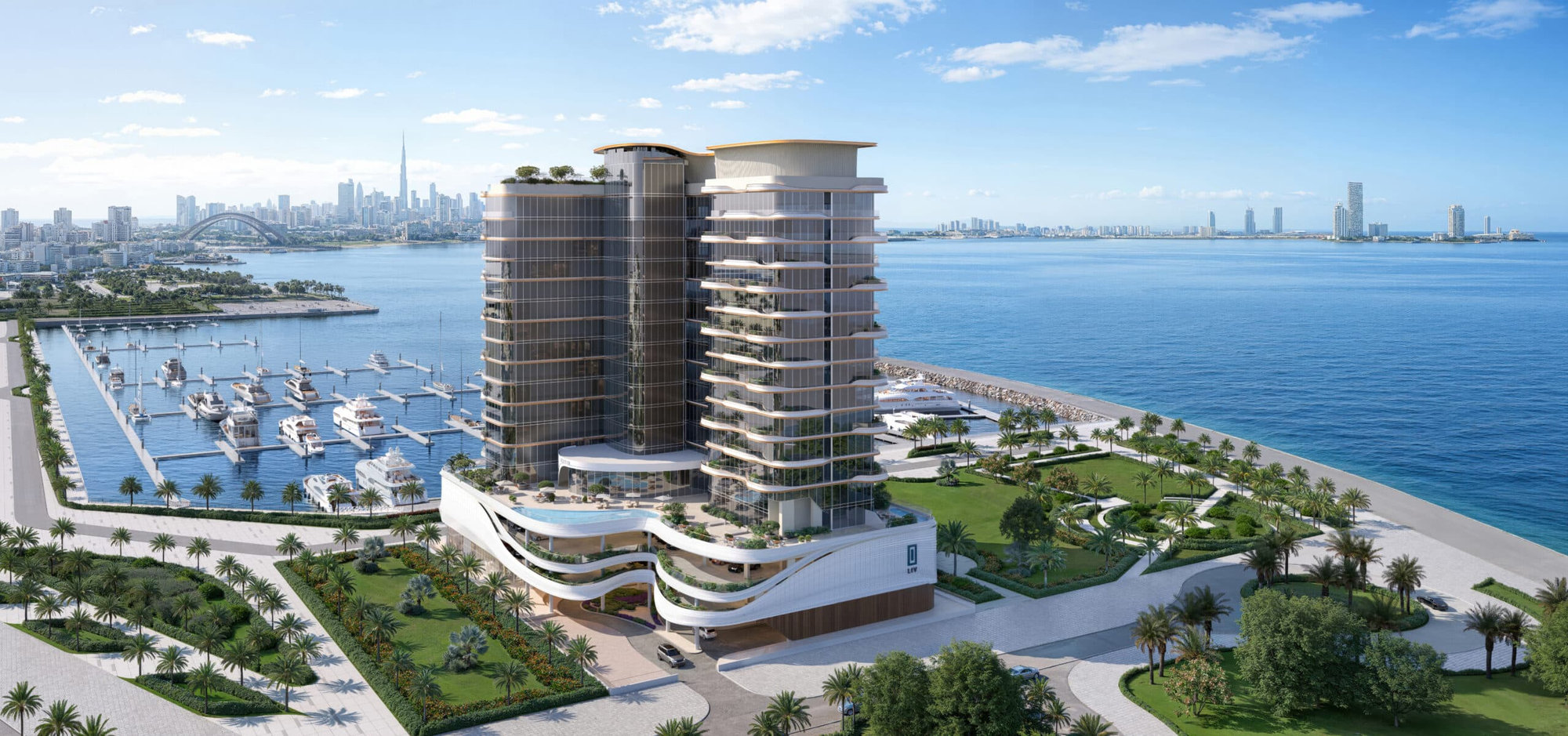בניין מודרני על קו החוף, LIV OCEANSIDE, עם מרפסות מעוגלות, שוכן לצד מרינה מלאה ביאכטות, מוקף בגינון ירוק ועצי דקל, ומשקיף על מפרץ כחול ושליו ועל קו הרקיע של העיר תחת שמיים בהירים. בניין מודרני על קו החוף, LIV OCEANSIDE, עם מרפסות מעוגלות, שוכן לצד מרינה מלאה ביאכטות, מוקף בגינון ירוק ועצי דקל, ומשקיף על מפרץ כחול ושליו ועל קו הרקיע של העיר תחת שמיים בהירים.