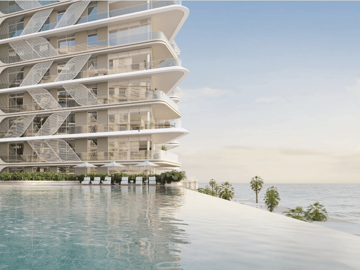 Fahid Beach Residence” הוא בניין מודרני רב-קומתי עם מרפסות מעוגלות המשקיפות על בריכת אינסוף, עצי דקל והאוקיינוס, תחת שמיים מעוננים חלקית בשעת השקיעה או הזריחה. כסאות נוח ושמשיות פזורים לאורך שפת הבריכה המזמינה. Fahid Beach Residence" הוא בניין מודרני רב-קומתי עם מרפסות מעוגלות המשקיפות על בריכת אינסוף, עצי דקל והאוקיינוס, תחת שמיים מעוננים חלקית בשעת השקיעה או הזריחה. כסאות נוח ושמשיות פזורים לאורך שפת הבריכה המזמינה.
