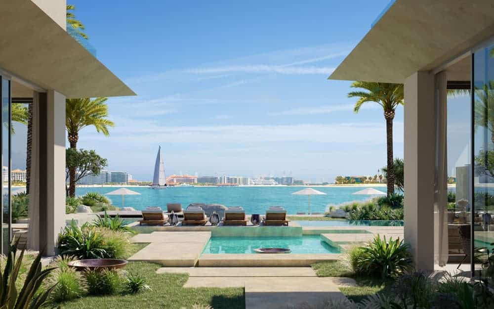 נוף הנשקף מווילה מודרנית במתחם Six Senses בפאלם ג’ומיירה, הכוללת בריכה פרטית, כסאות נוח, גינון שופע ועצי דקל, המשקיפה על מים כחולים וצלולים, עם קו הרקיע של העיר והבניין הייחודי בצורת מפרש הנראה מרחוק. נוף הנשקף מווילה מודרנית במתחם Six Senses בפאלם ג'ומיירה, הכוללת בריכה פרטית, כסאות נוח, גינון שופע ועצי דקל, המשקיפה על מים כחולים וצלולים, עם קו הרקיע של העיר והבניין הייחודי בצורת מפרש הנראה מרחוק.