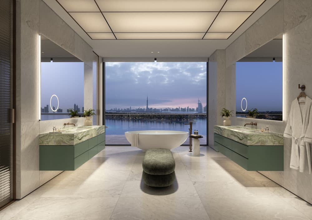 חדר רחצה מודרני ומפואר באתר הנופש היוקרתי Six Senses, הכולל אמבטיה עומדת, כיורי רחצה בצבע ירוק ורצפות שיש; חלון מהרצפה עד התקרה חושף את קו הרקיע של פאלם ג’ומיירה בשעת בין ערביים, והכל משולב בתאורה אווירתית וחלוק תלוי על הקיר. חדר רחצה מודרני ומפואר באתר הנופש היוקרתי Six Senses, הכולל אמבטיה עומדת, כיורי רחצה בצבע ירוק ורצפות שיש; חלון מהרצפה עד התקרה חושף את קו הרקיע של פאלם ג'ומיירה בשעת בין ערביים, והכל משולב בתאורה אווירתית וחלוק תלוי על הקיר.
