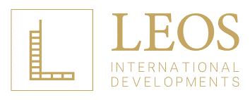 לוגו של חברת LEOS International Developments, הכולל את האות L מעוצבת בצורת מלבנים הדומים לבניינים בצד שמאל. בצד ימין, הכיתוב HADLEY HEIGHTS מופיע מעל שם החברה בצבע זהב: LEOS מעל International Developments. לוגו של חברת LEOS International Developments, הכולל את האות L מעוצבת בצורת מלבנים הדומים לבניינים בצד שמאל. בצד ימין, הכיתוב HADLEY HEIGHTS מופיע מעל שם החברה בצבע זהב: LEOS מעל International Developments.
