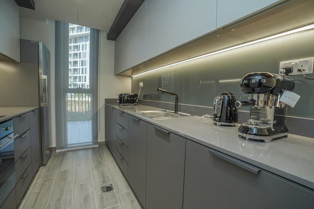 מטבח מודרני בפרויקט “Noor Midtown” של חברת Deyaar, הכולל ארונות אפורים, משטח עבודה אלגנטי, מכשירי חשמל מובנים, תאורה תחת-ארון ומכשירי חשמל קטנים. חלון גדול ממלא את החלל התוסס במרכז דובאי באור טבעי. מטבח מודרני בפרויקט "Noor Midtown" של חברת Deyaar, הכולל ארונות אפורים, משטח עבודה אלגנטי, מכשירי חשמל מובנים, תאורה תחת-ארון ומכשירי חשמל קטנים. חלון גדול ממלא את החלל התוסס במרכז דובאי באור טבעי.