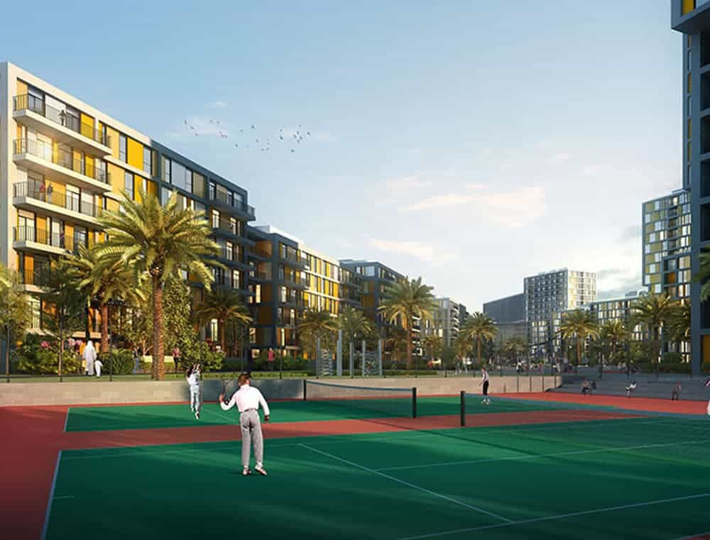 מתחם מגורים מודרני, “Noor Midtown” מבית Deyaar, כולל עצי דקל ומספר בנייני דירות בני קומות בינוניות. בחזית, אנשים נהנים ממשחק טניס על מגרש ירוק ואדום תחת שמיים כחולים וצלולים. מתחם מגורים מודרני, "Noor Midtown" מבית Deyaar, כולל עצי דקל ומספר בנייני דירות בני קומות בינוניות. בחזית, אנשים נהנים ממשחק טניס על מגרש ירוק ואדום תחת שמיים כחולים וצלולים.